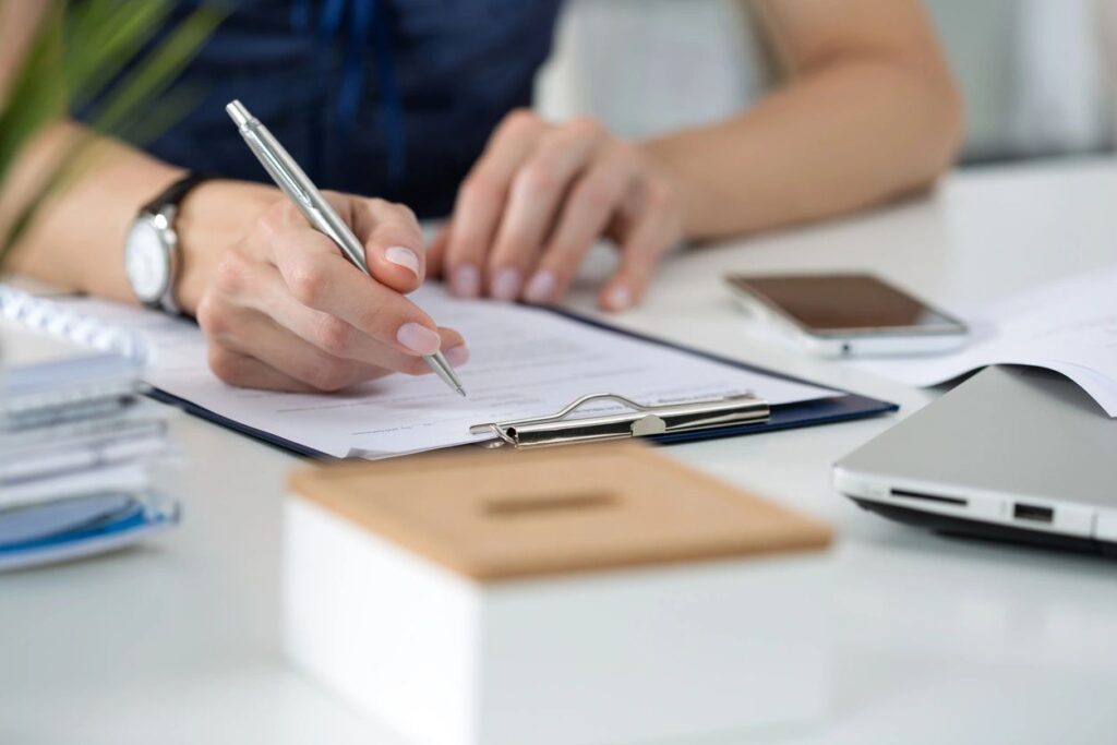 woman is sitting behind a desk filling out a piece of paper